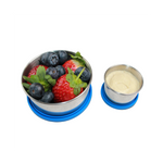 Metal container with berries and a small cup of hommus on a white background